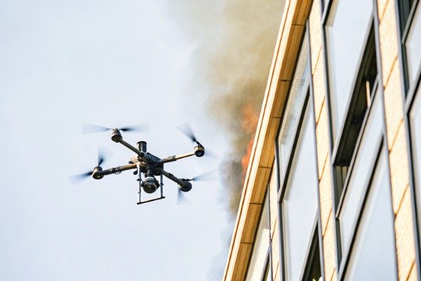 Firefighting drone flight Drone firefighting mid-flight near burning building (ID#3)