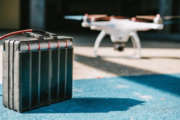 Drone battery pack Heavy drone battery pack with drone in background (ID#3)