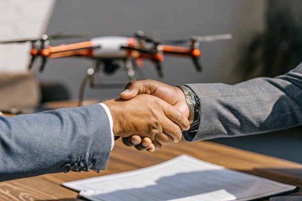 Handshake between two business professionals with drone background (ID#1)