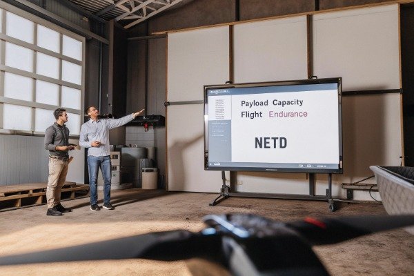 Drone specs discussion Two men discussing drone specs on screen indoors (ID#2)