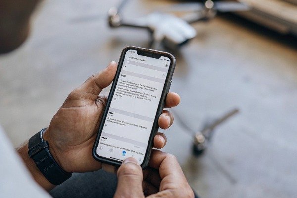 Person holding smartphone scrolling LinkedIn drone page (ID#5)