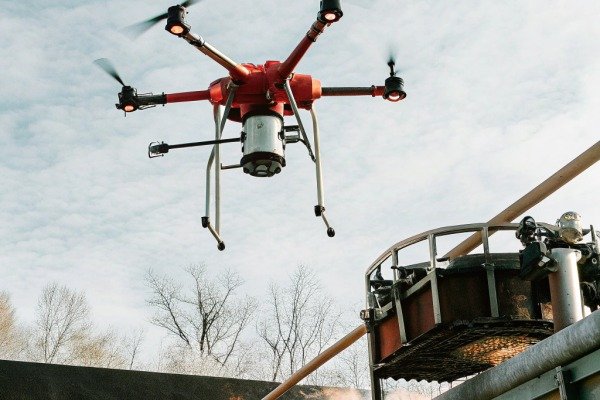 طائرة بدون طيار حمراء تحلق فوق معدات صناعية (ID#1)