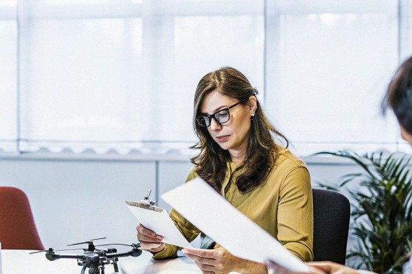 مراجعة المستندات Person reviewing documents with drone on table (ID#5)
