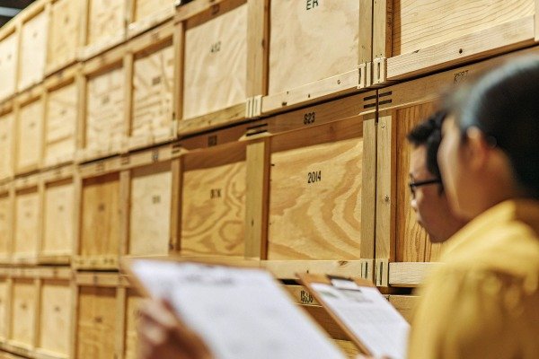 Warehouse inventory check Two people checking inventory in a warehouse with wooden crates (ID#2)