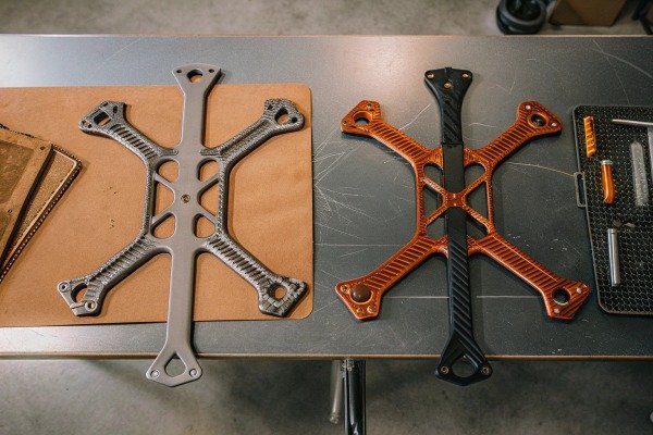 Drone frames on table Two drone frames, one grey and one orange, on a table (ID#5)