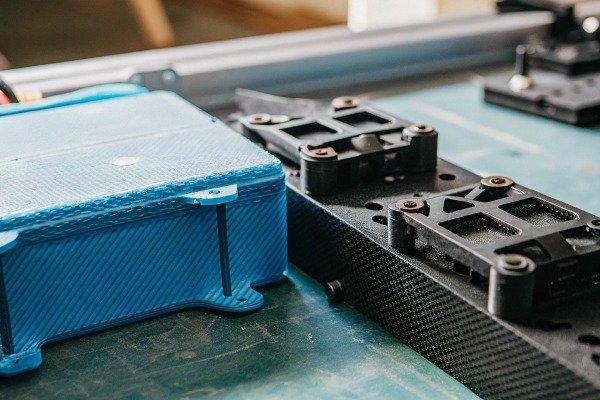 Blue drone battery pack and other drone components on a workbench (ID#4)