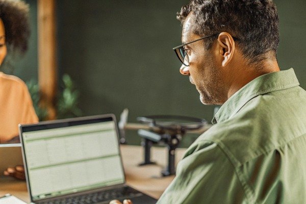 Man working on laptop with drone in background (ID#3)