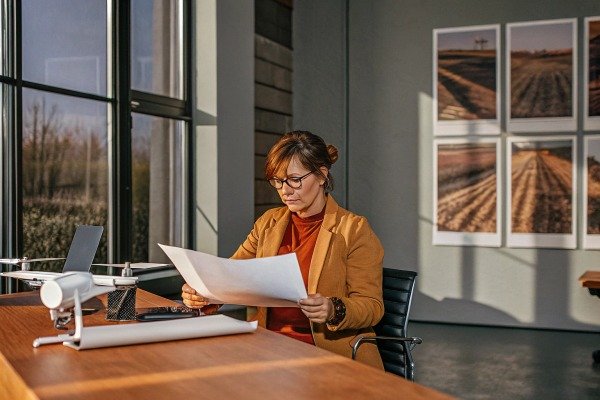 Revisión de documentos Mujer revisando documentos en una oficina con un dron cerca (ID#5)