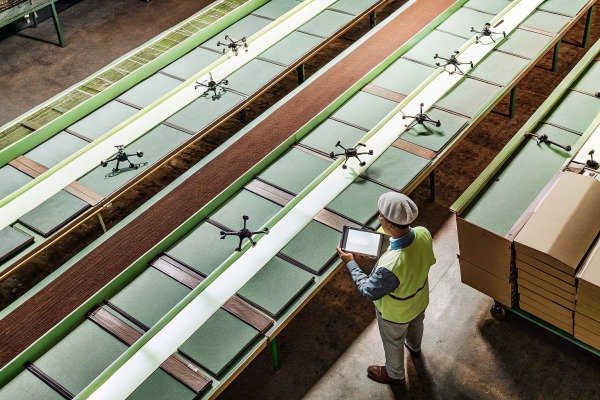 Worker inspecting drones on conveyor belt (ID#4)