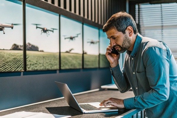 Man working on laptop with drone images on wall (ID#5)