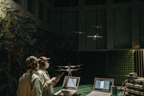Technicians controlling drones indoors with laptops (ID#4)
