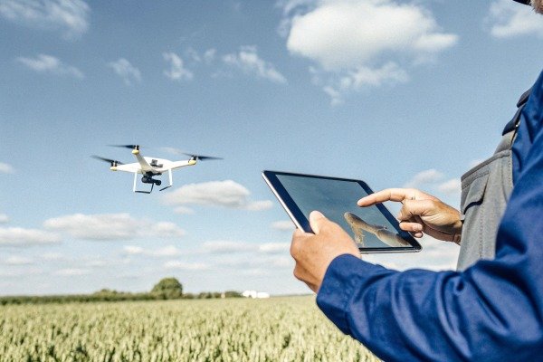 Person controlling drone with tablet in field (ID#5)