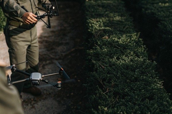 Person holding drone near green bushes (ID#5)