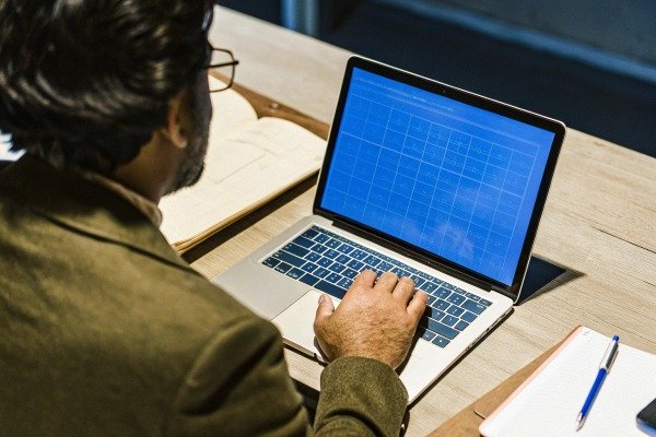 Man working on laptop at wooden desk (ID#4)