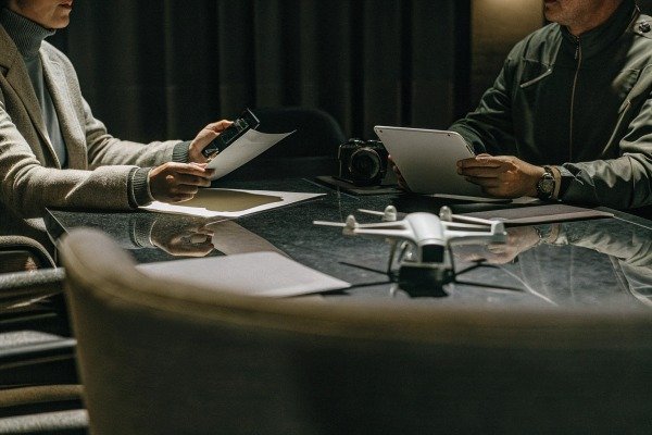 Drone meeting People discussing drone and camera on table (ID#4)