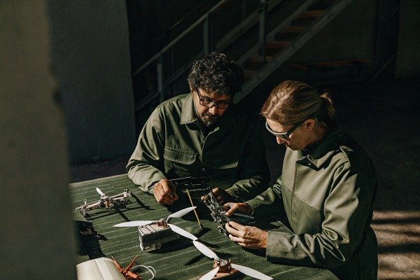 Two people inspecting drone parts indoors (ID#5)