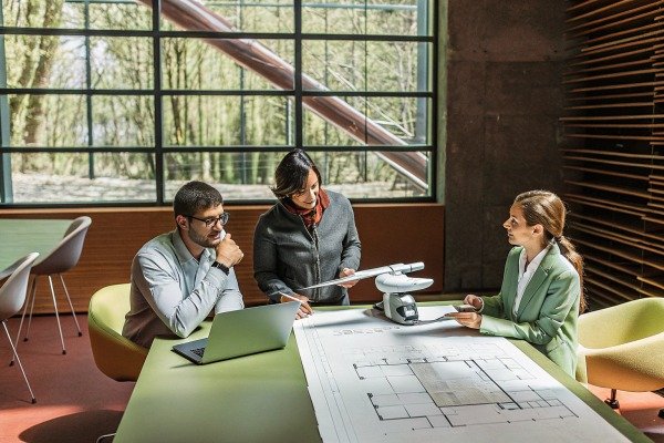 Team discussing architectural plans with drone model (ID#5)