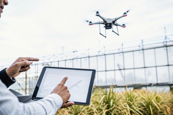 Person controlling drone with tablet in field (ID#5)