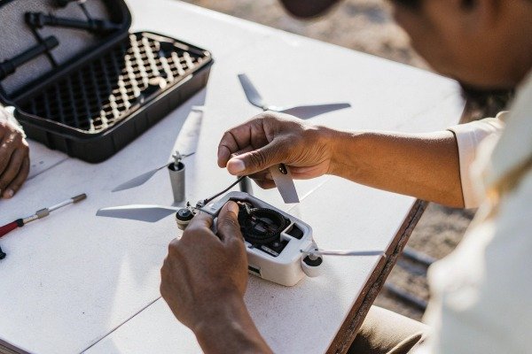 Hands assembling drone parts on table (ID#2)