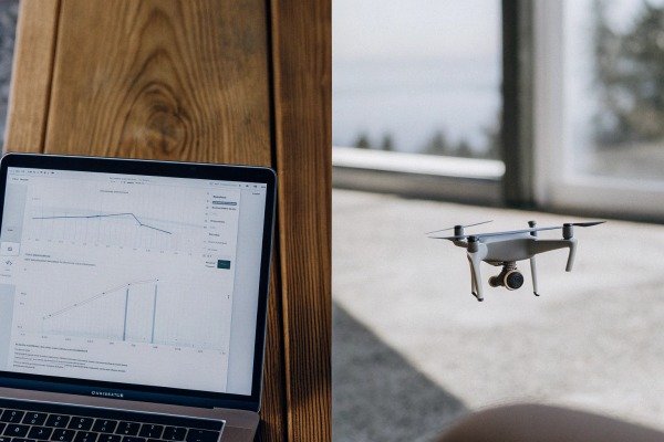 Drone flying indoors near laptop showing data (ID#4)