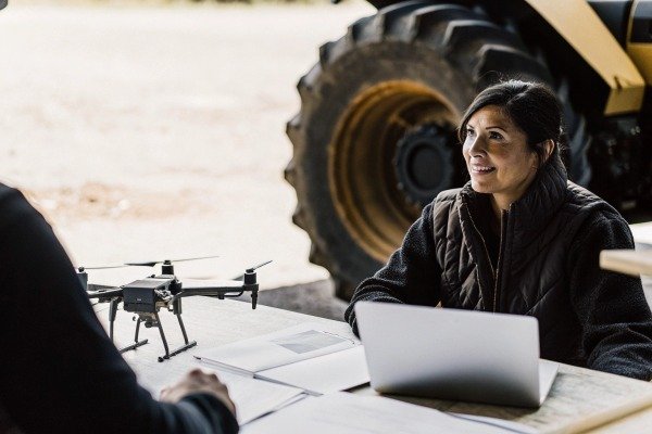 Woman discussing drone with laptop and tractor (ID#5)