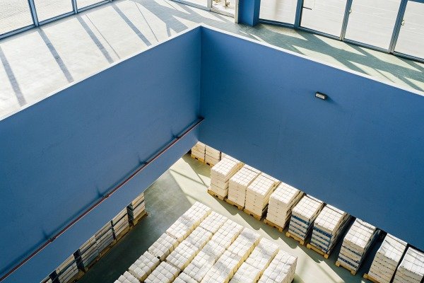 Warehouse interior with stacked pallets and blue walls (ID#2)