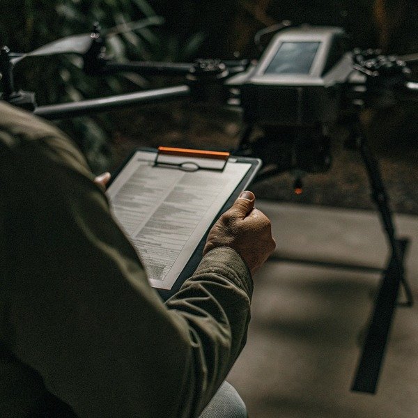 Person holding clipboard near drone indoors (ID#1)