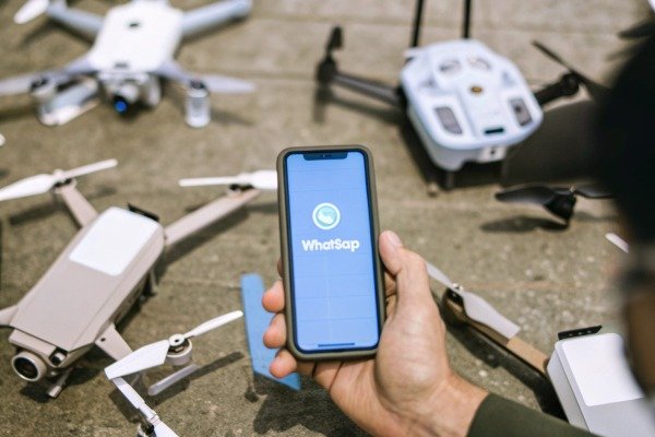 Hand holding phone with WhatsApp app and drones (ID#3)