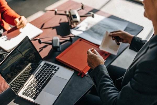 People discussing drone data at table with laptop (ID#5)