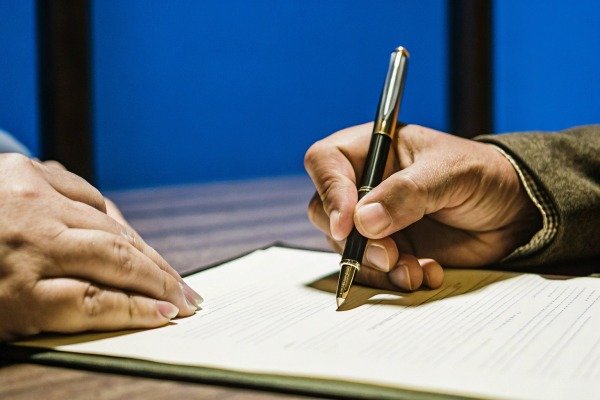 Close-up of hands signing document with pen (ID#3)