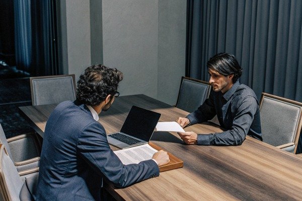 Two men discussing documents at conference table (ID#4)