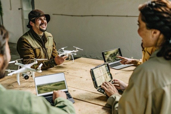 Group discussing drones with laptops and drone models (ID#4)