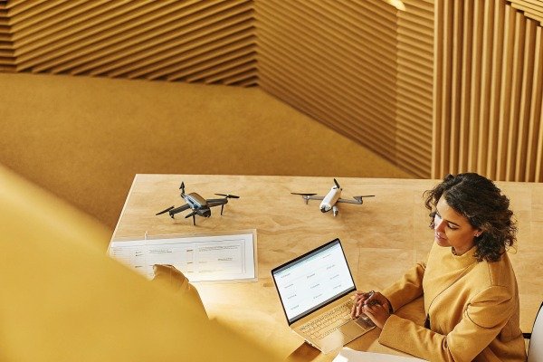 Woman working on laptop with drone models on table (ID#5)