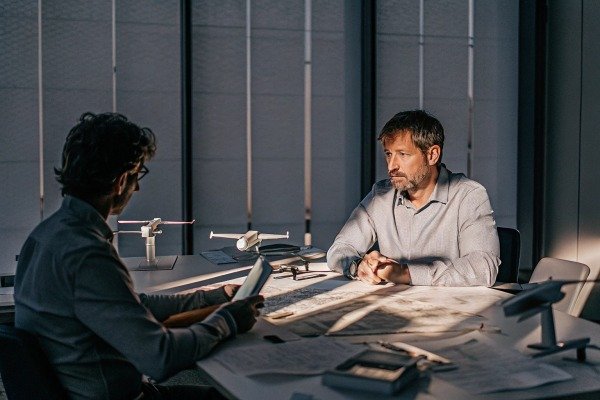 Drone design meeting Two men discussing drone models at table (ID#5)