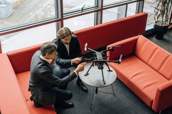Two men examining drone on table in office setting (ID#5)