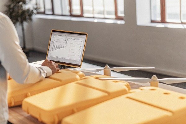 Trabajando con drones Persona trabajando en un portátil cerca de piezas de drones (ID#4)