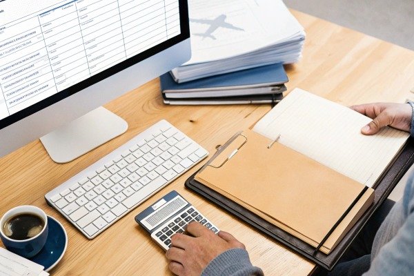 Person using calculator and clipboard at desk (ID#2)