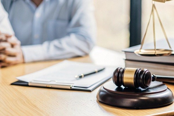Legal gavel and scales on desk with person (ID#2)