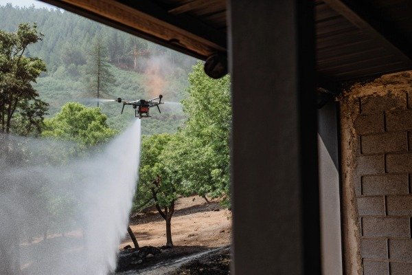 Drone spraying water over forested area for fire control (ID#5)