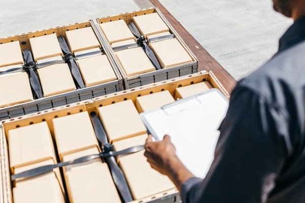 Worker with clipboard inspecting boxes of drone propellers in a warehouse (ID#2)