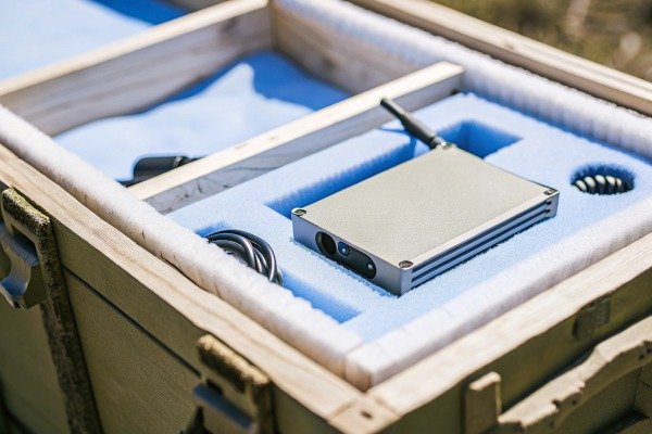 Compact electronic tracking device secured inside a foam-lined protective wooden transport crate (ID#4)