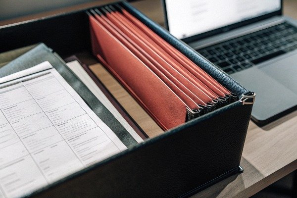 Organized Office File Storage Organized red file folders in a black storage box next to a laptop computer (ID#2)
