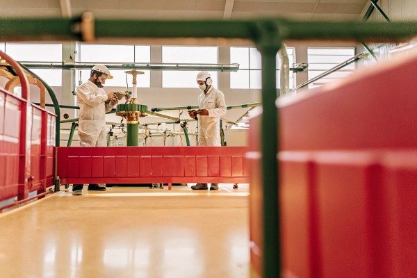 Industrial Facility Technicians Working Technicians in protective suits working on industrial machinery inside a clean manufacturing facility (ID#4)