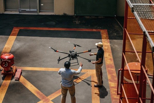 Two operators preparing a large hexacopter drone for flight in an outdoor industrial area (ID#4)