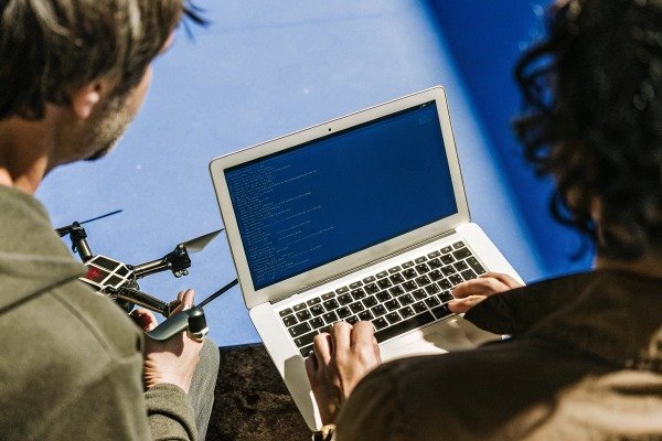 Developers programming a drone using a laptop with code on the screen (ID#3)