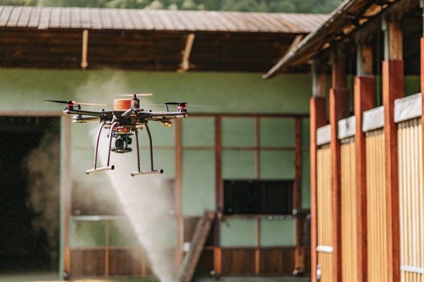 Industrial drone flying near a wooden building during a field operation (ID#5)