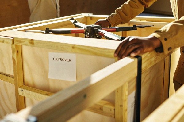 Hands carefully packing a Skyrover drone into a wooden shipping crate (ID#5)
