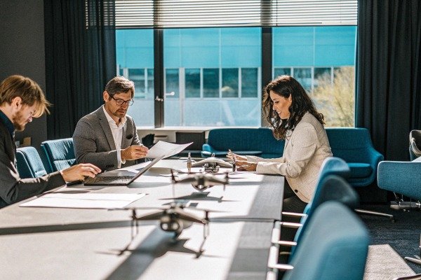 Professionals in a business meeting with small drones on the conference table (ID#4)
