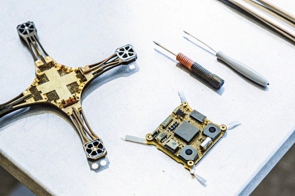 Disassembled drone frame and electronic circuit board with precision tools on a workbench (ID#2)