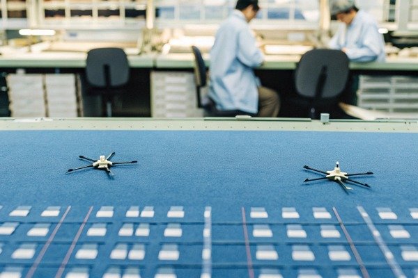 Miniature drone components placed on a blue surface in a clean manufacturing laboratory environment (ID#4)